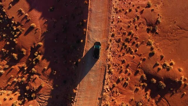 Modern car driving at Monument Valley desert by sunset. Cinematic top view off-road at red rock sandstone landscape in Utah.