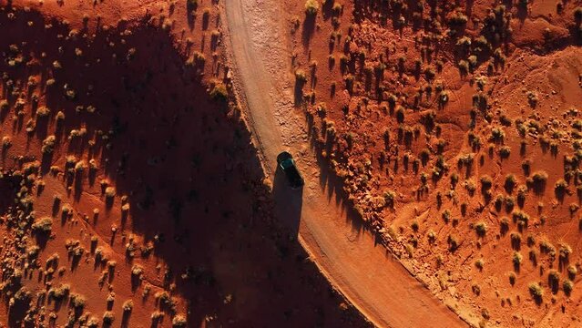 Modern car driving at Monument Valley desert by sunset. Cinematic red rock sandstone landscape in Utah.