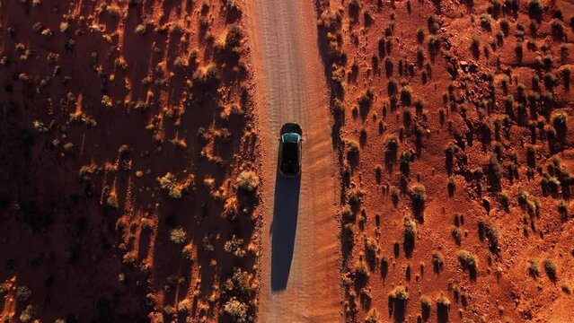 Modern car driving at Monument Valley desert by sunset. Cinematic top view at red rock sandstone landscape in Utah.