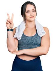Young hispanic girl wearing sportswear and towel smiling with happy face winking at the camera...