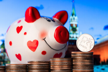 Coin with the symbol of the Russian ruble and a piggy bank against the background of the Moscow...