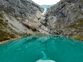 aerial picture from drone over blue mountain lake of briksdalsbreen glacier in norway 