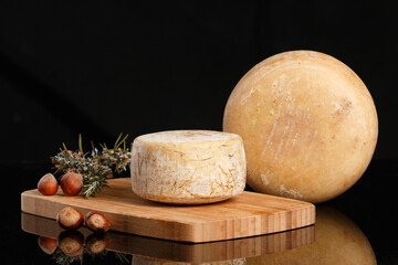 Artisanal and natural whole cheese, placed on a wooden board and without labels.