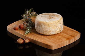 Artisanal and natural whole cheese, placed on a wooden board and without labels.