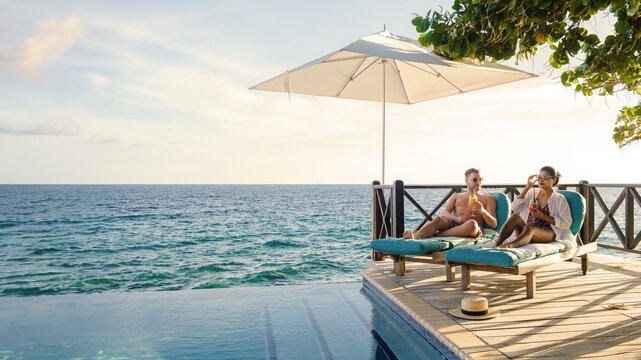 Curacao A Couple Man And Woman Mid Age Relaxing By The Swimming Pool During Vacation, Men And Girl By The Pool In Curacao During Holiday At A Tropical Island Luxury Vacation