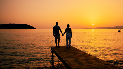 a couple of men and women on a wooden jetty looking the sunset on the sea, men and women watching a...