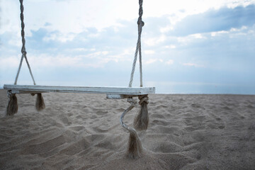 Fototapeta premium Wooden swing on the beach. The coast of the Indian Ocean. A deserted beach. The concept of summer holidays.