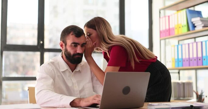 Female employee whispers secret into male colleague ear