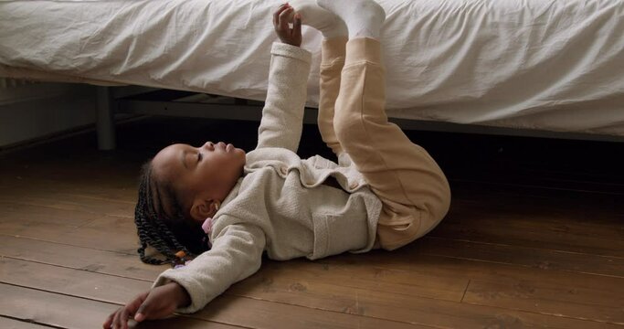 Pretty African little girl lying on the floor. she does not know what to do, mother does not to put much attention to kid