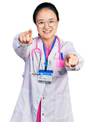 Fototapeta premium Young chinese woman wearing doctor uniform and stethoscope pointing to you and the camera with fingers, smiling positive and cheerful