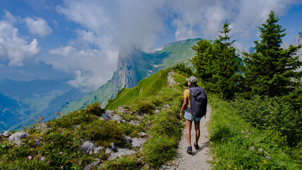women hiking in the Swiss Alps mountains during summer vacation with a backpack and hiking boots....
