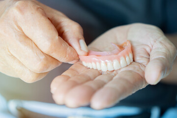 Close-up in the hand of a pensioner removable dentures. Stomatology, dental prosthetics concept.
