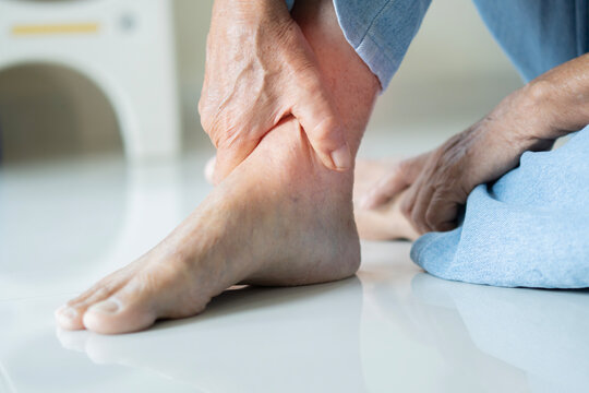 Cropped shot of senior man sitting on floor and relaxing his feet with a massage.