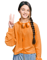 Young brunette girl with long hair wearing sweatshirt and headphones showing and pointing up with fingers number three while smiling confident and happy.