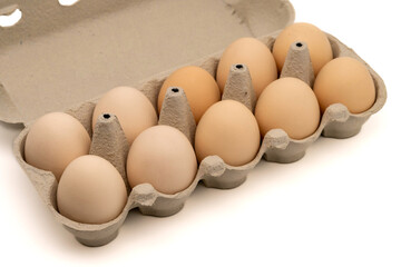 Cardboard egg box with ten chicken eggs isolated on white background with copy space. Close-up view.