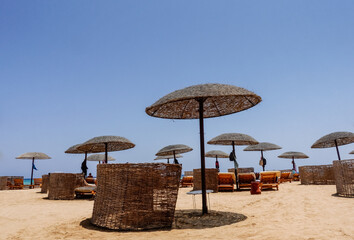 beach area with umbrellas and beach chairs with sand and deep blue sky on vacation