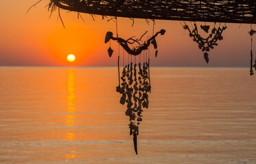 jewelry made of shells hanging on a parasol during sunrise at the red sea