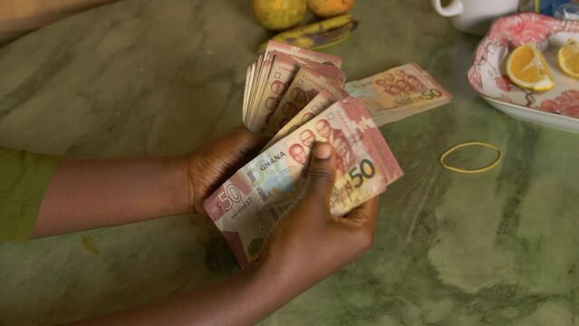 Black female woman hand counting Ghanaian Cedi paper bill from Republic of Ghana Africa