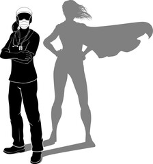 A doctor or nurse woman in silhouette wearing PPE mask and scrubs revealed as a super hero by her shadow.