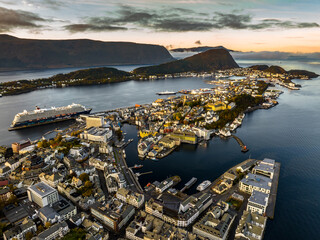 scenic aerial view over city of Alesund in the morning during sunrise with a big cruise ship in port