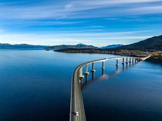 aerial view of Tresfjord Bridge with mountains on background with reflections on water in norway