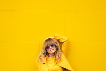 middle aged adult woman wearing yellow clothes on yellow wall outdoors