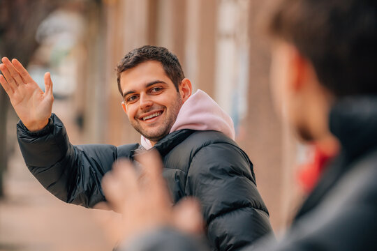 friends greeting each other on the street with their hands