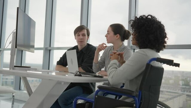 African american girl in wheelchair on job interview in modern office. Human resources workers man woman interviewing candidate to work. Usual life of special needs person, getting job concept.