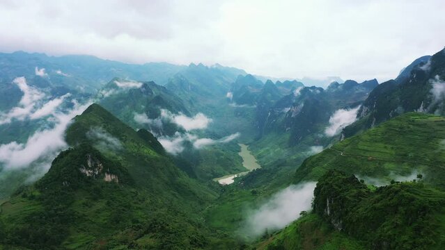 Drone of green mountains, river and nature for travel background, eco tourism location and holiday. Aerial view of forest landscape, countryside road or highway and clouds in Vietnam, Ma Pi Leng Pass