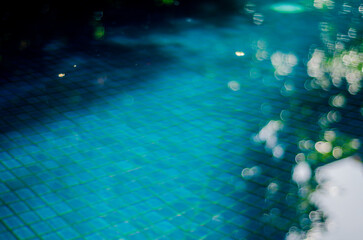Blurred and abstract light reflected on the turquoise water of an hotel pool background