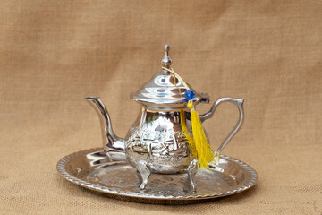 close up of moroccan traditional tea pot and glass on a silver plate