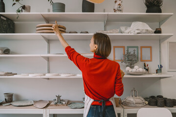 Woman working pottery workshop or ceramic shop. Owner of craft small business
