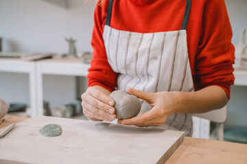 Female hands working with clay makes ceramic tableware on pottery workshop.