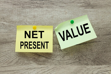 Net present value NPV two stickers, green and yellow, riveted to a wooden background. text