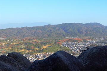 Obraz premium 滋賀県 菩提寺山の岩越しにみる湖南市と色づく山