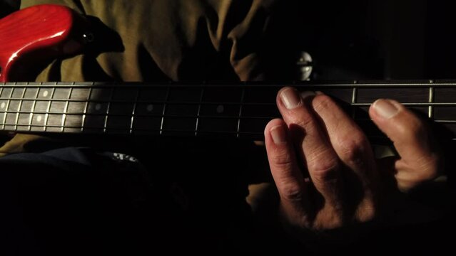 Man playing bass guitar showing left hand finger technique