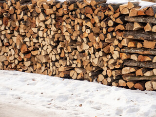 stack of chopped firewood in the snow