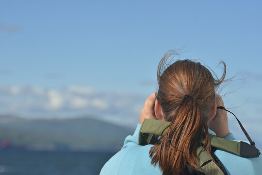 young woman in the park looking through binoculars. 