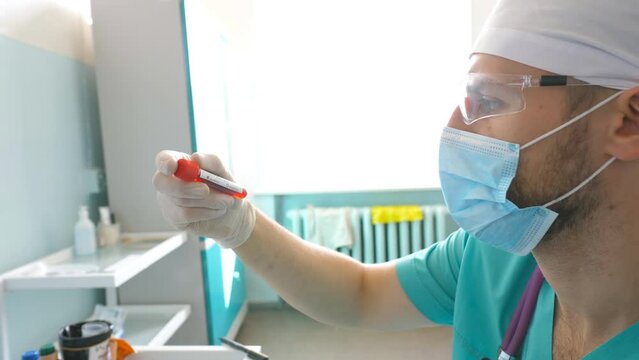 Scientist examining test tube with blood sample to coronavirus. Lab worker with protective gloves testing blood samples to COVID-19. Concept of health and safety life from pandemic of corona virus