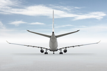 Rear view of a wide body passenger aircraft isolated on bright background with sky