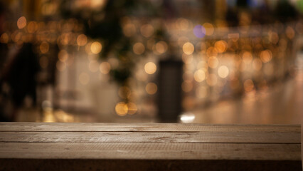 Empty wooden table top on blur light golden bokeh of cafe restaurant, bar in a dark background.