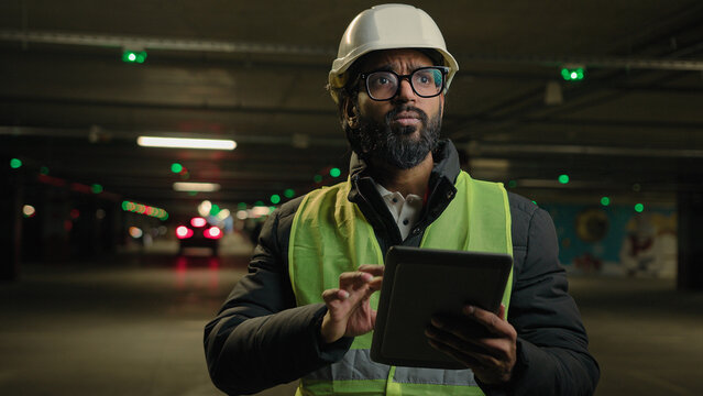 Foreman inspecting parking lot underground urban industrial heavy industry engineer Arabian man Indian builder in hard hat architect manufacture worker digital tablet talking video call conference