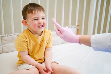 The woman doctor is using a special cream to soothe the baby irritated skin. Kid aged about two years (one year eleven months)