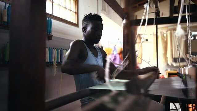 Man, loom and fabric or textiles and cotton production at clothing factory, manufacturing and craftsmanship. Black male person, warehouse and weaving thread or industry, wool and designer or skill