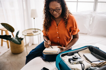 Mature traveler ticking off her packing list at home