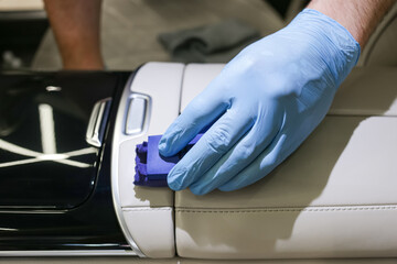 The process of applying a protective ceramic composition to the leather interior of the car interior. The concept of protecting and restoring the leather interior of the car. Automotive ceramics.  - obrazy, fototapety, plakaty