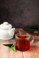 Glass cup of black tea, on wooden table. Hot beverage.