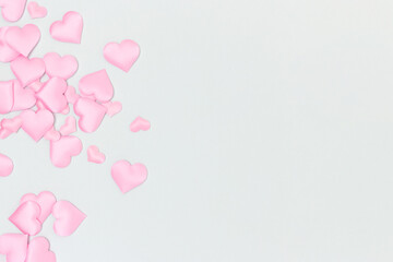 Pink textile hearts confetti scattered on a blue background. Place for your design.