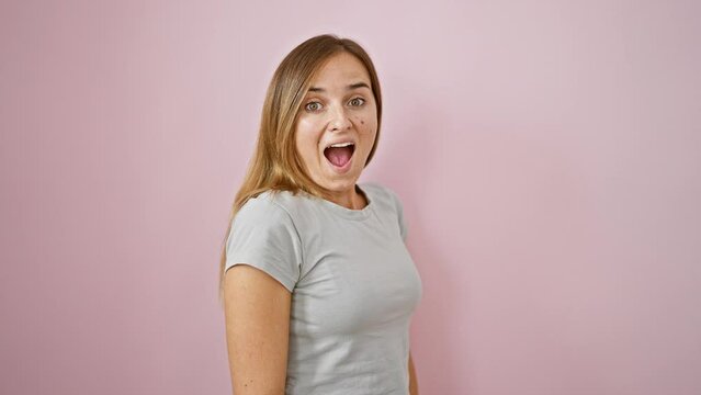 Wow! cheerful young blonde woman, amazed, covering mouth with hands, standing over pink isolated background. beautiful expression of happy surprise!