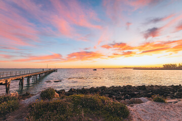 Robe jetty with fishermen during sunrise while viewed towards the ocean from the shore, Limestone...